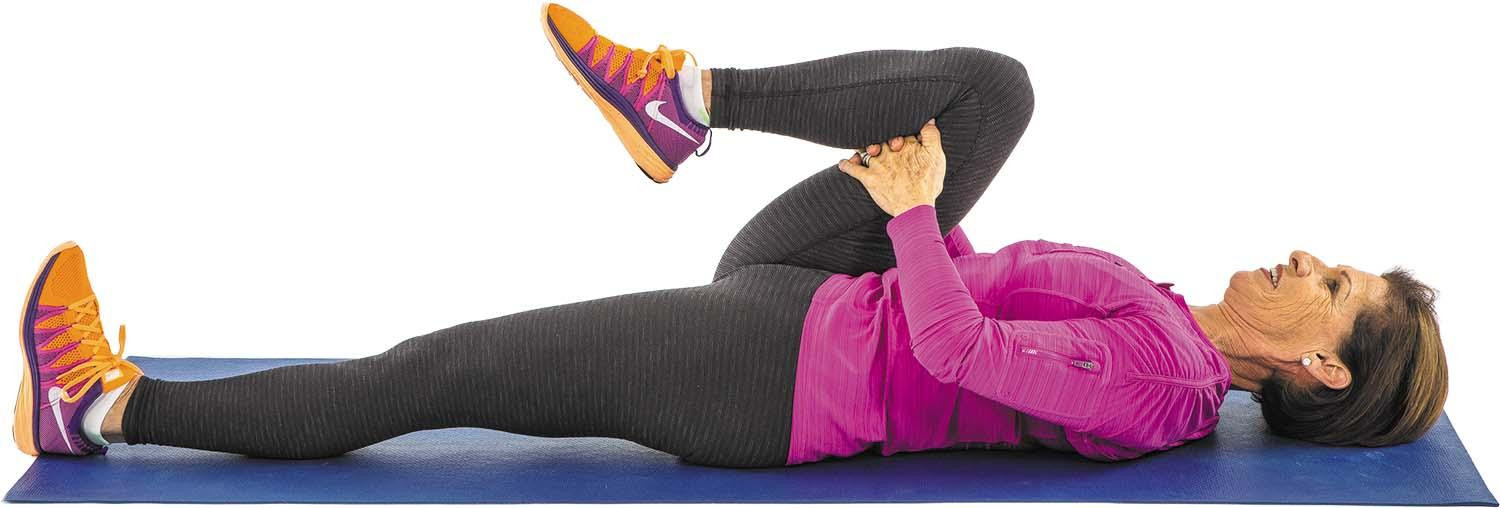 A woman performs the single knee pull exercise as described in the article.